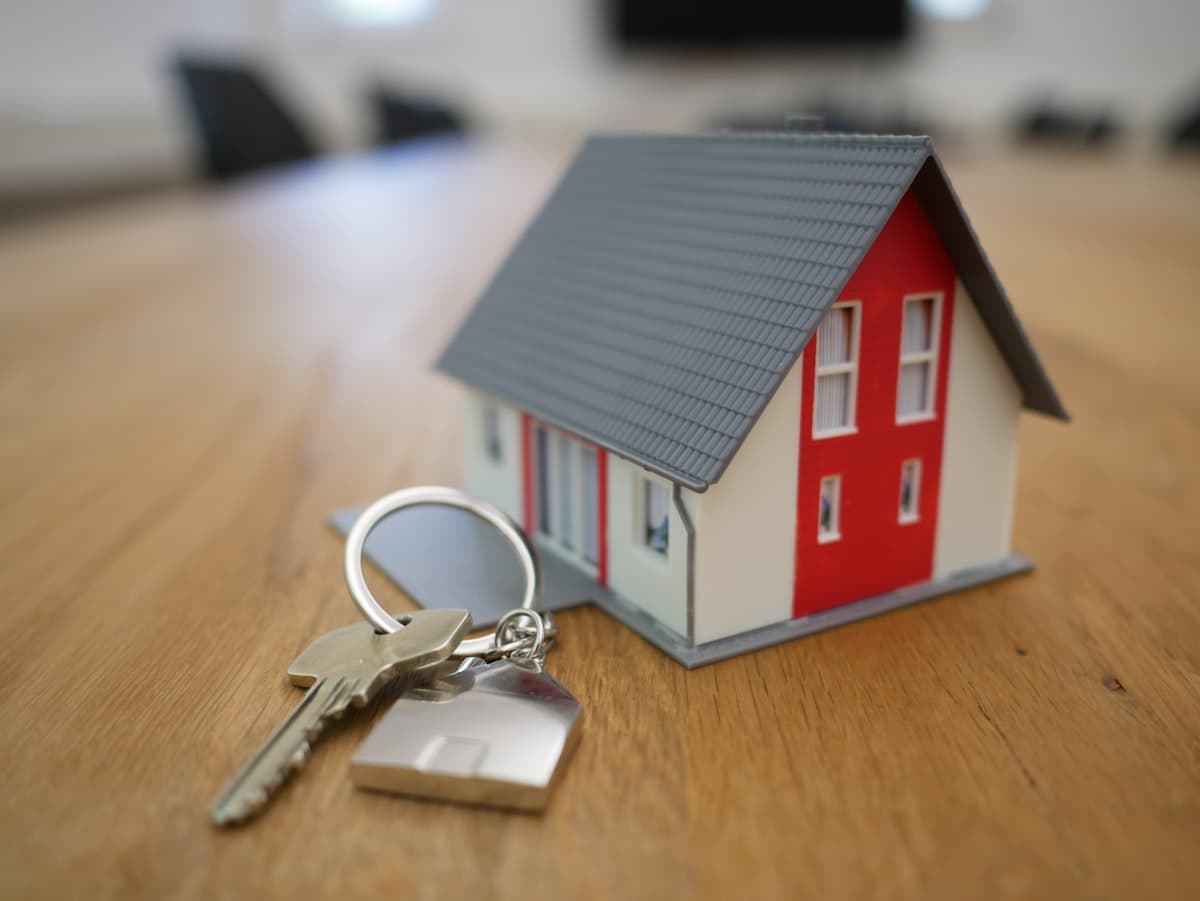 Hausschlüssel neben einem Miniaturhaus